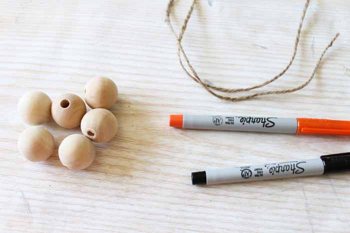 wood beads, twine, and markers on a table