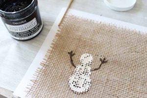 top shot of white snowman being painted on burlap