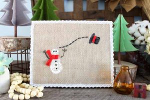 winter snowman painted on burlap attached to wooden panel