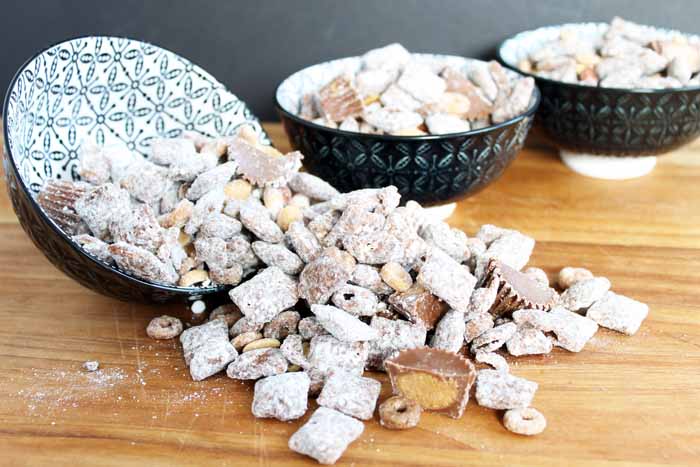 chocolate and peanut butter muddy buddies spiling out of a bowl