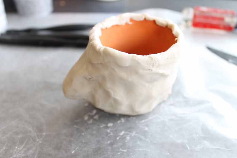 shaping clay around a terracotta pot