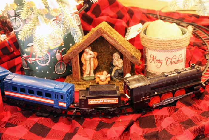 A toy train around a tree with a nativity scene