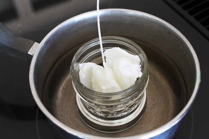 adding beeswax to a small mason jar in a pot