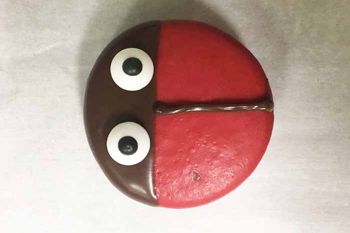 close up shot of red cookie with candy eyes