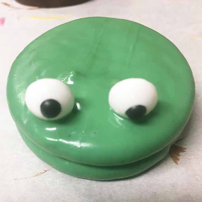 adding candy eyeballs to a dipped oreo cookie