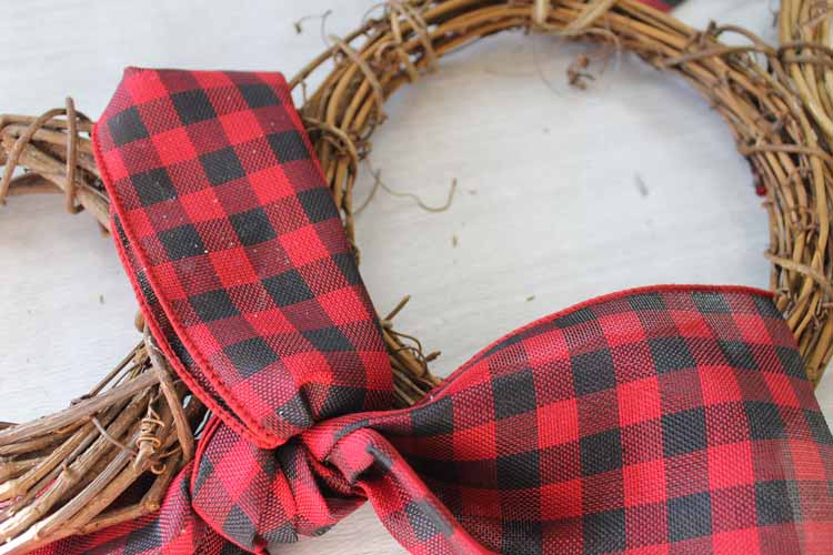 adding plaid ribbon to a snowman wreath