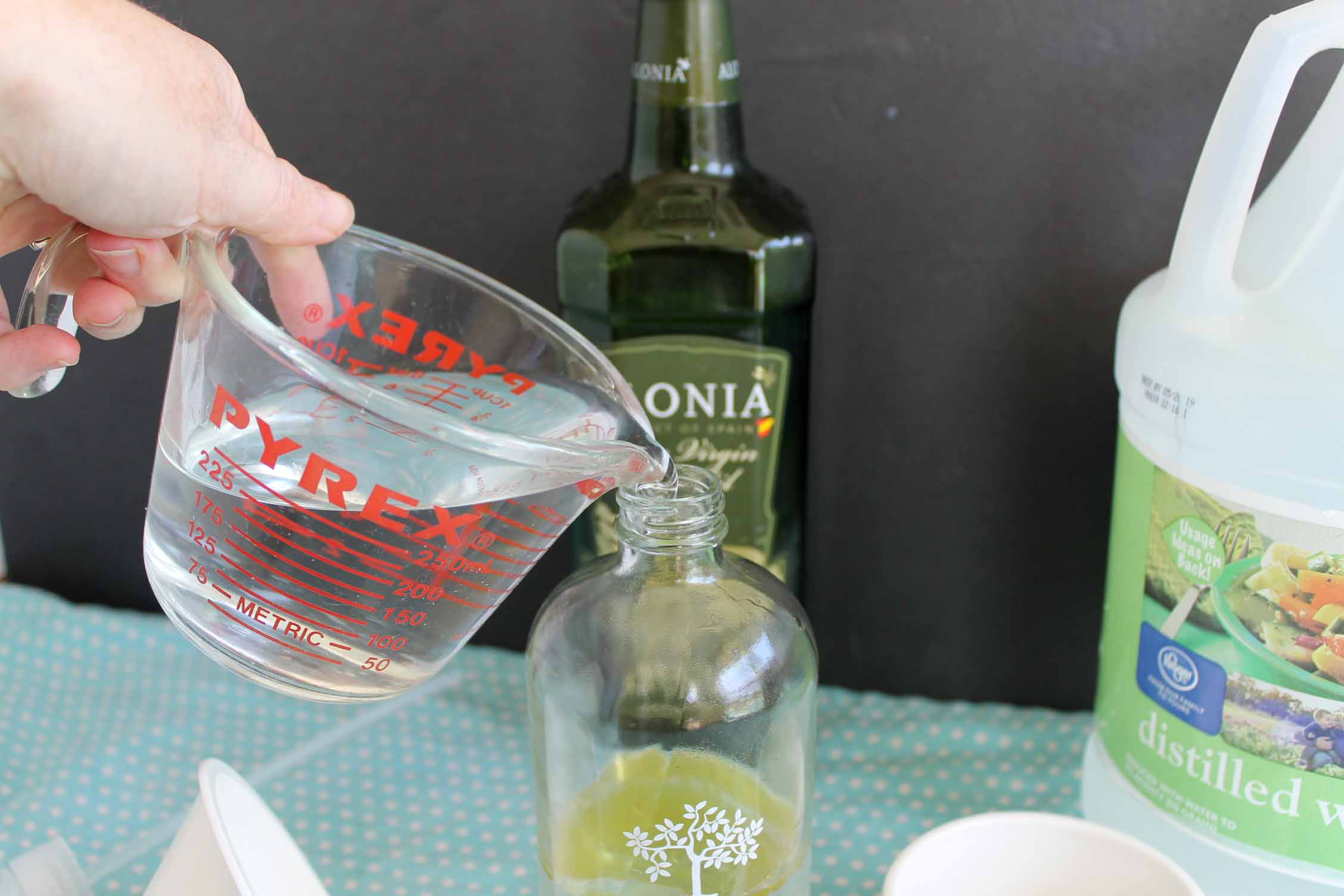 adding vinegar to homemade furniture polish in a glass bottle