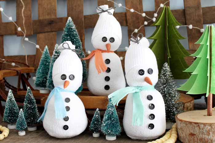Three sock snowmen and decorative Christmas trees.