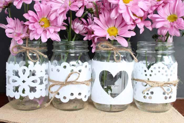 Mason jars used as vases with cut felt designs and twine wrapped around them.