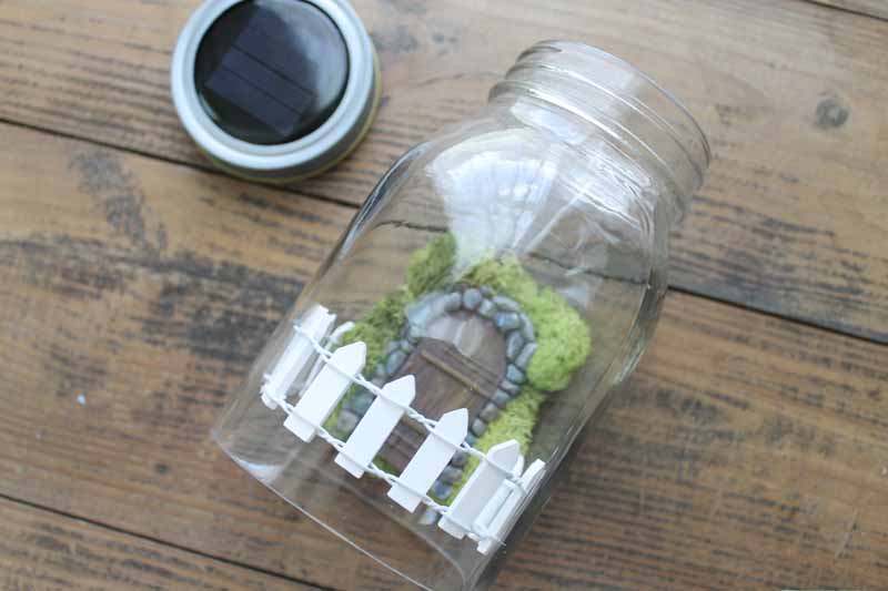 adding a fairy garden door and fence to a mason jar