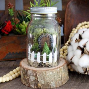 jar on a wood slice with a mini fairy garden inside