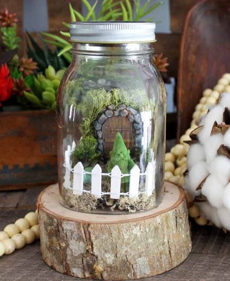 jar on a wood slice with a mini fairy garden inside