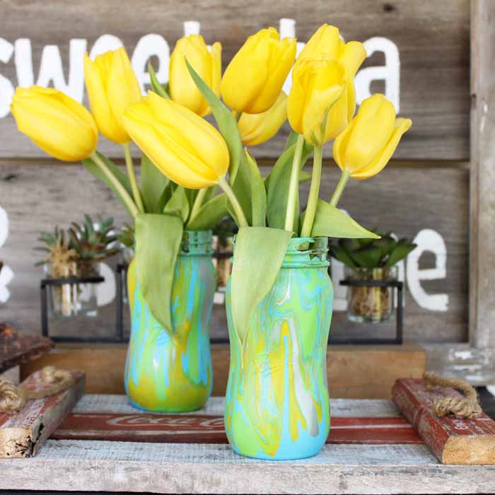 yellow flowers in mason jars decorated with acrylic pour painting technique