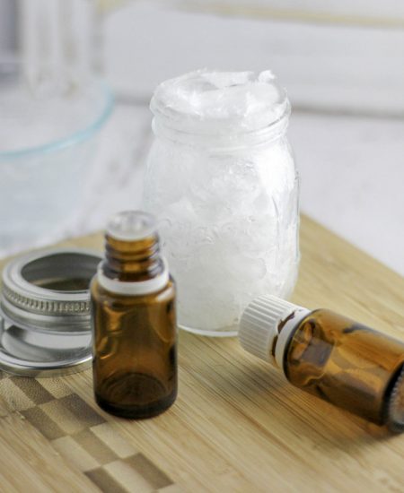 A glass bottle sitting on a table, with Essential oil and Container