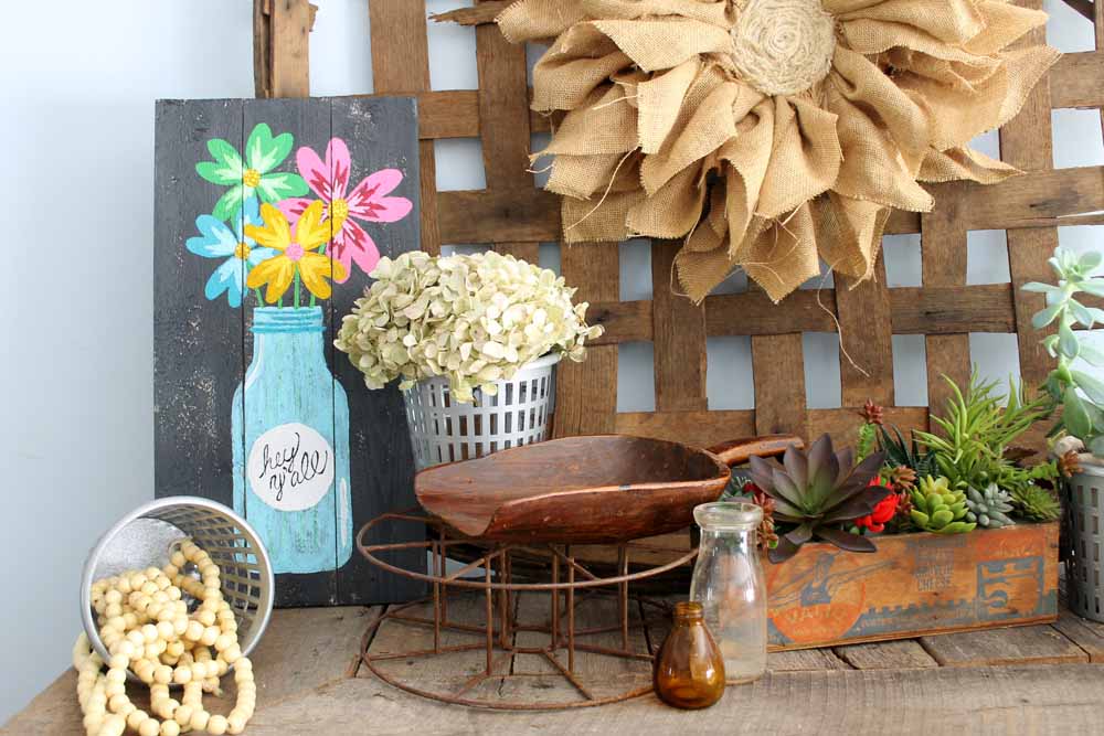 painted pallet art on a mantel with other objects
