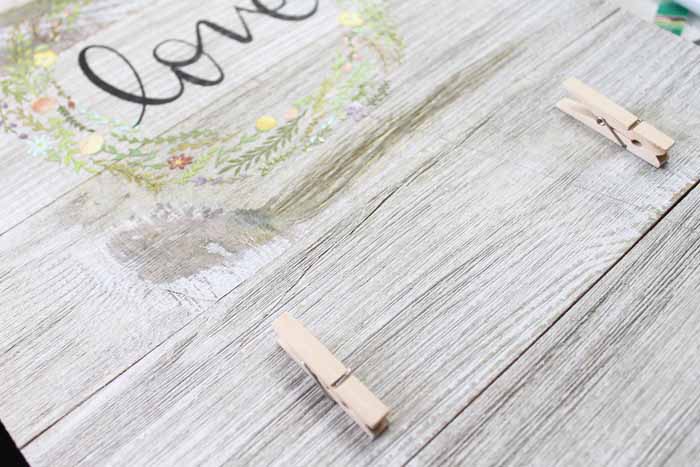 adding clothespins to rustic wood board