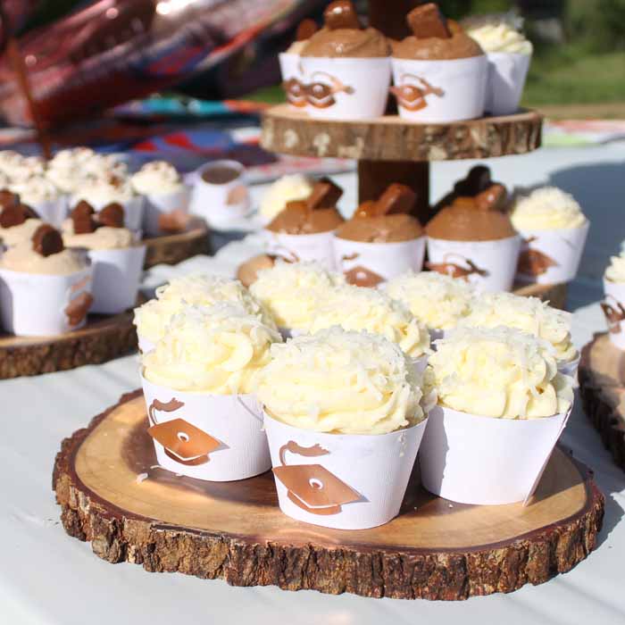 graduation cupcakes with graduation cap wrappers on rustic wooden planks