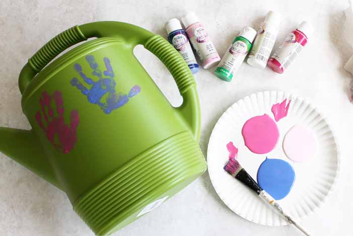 adding handprints onto a plastic watering can