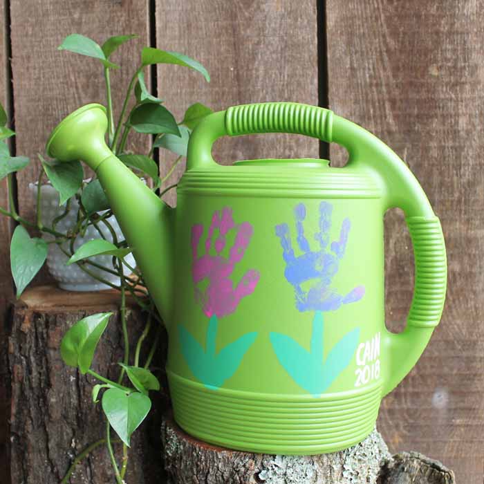 handprint flowers watering can on a stump