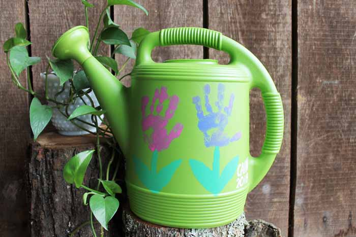 watering can with handprint flowers painted on it