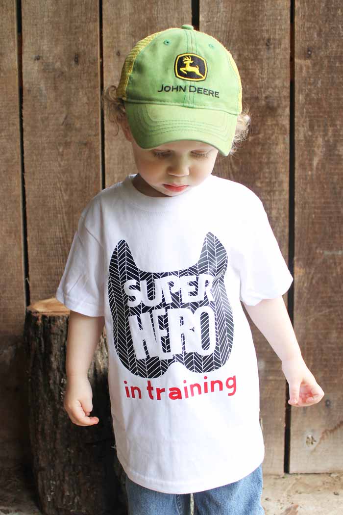 A little boy wearing a hat and a super hero in training shirt