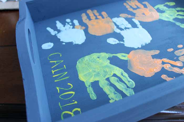 toddler handprints on the bottom of a tray in various colors