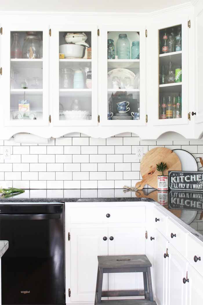 Glass front cabinets in a farm kitchen with mason jars and other rustic decor.