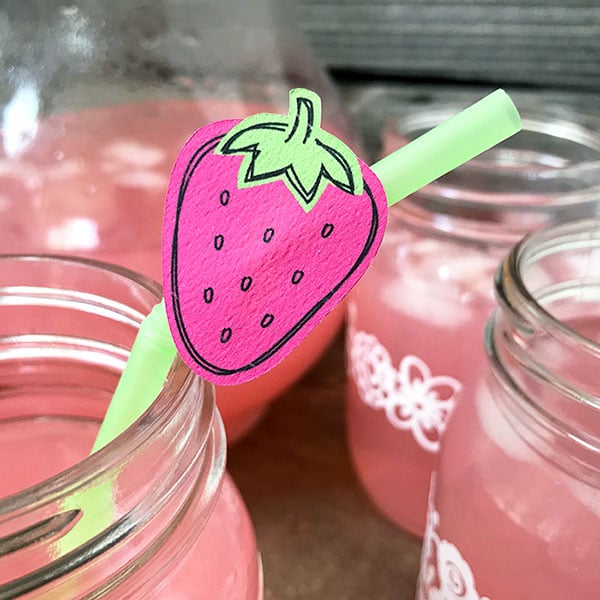 Decorating a straw for a summer party with strawberry decor.