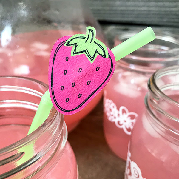 Decorating a straw for a summer party with strawberry decor.