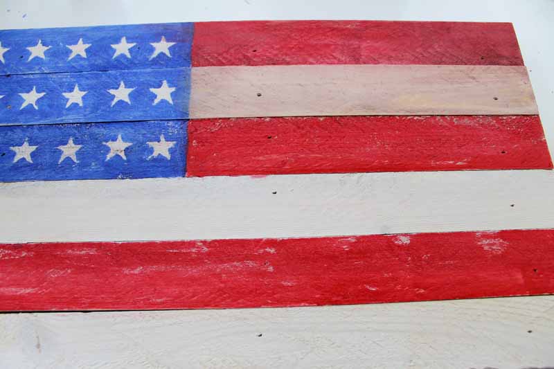 Distress painting on a rustic wooden flag.