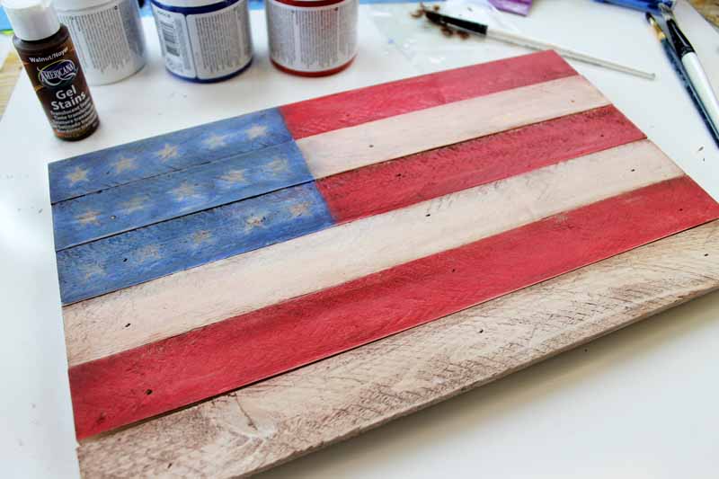 painting the red stripes of a rustic flag for your Americana decor.