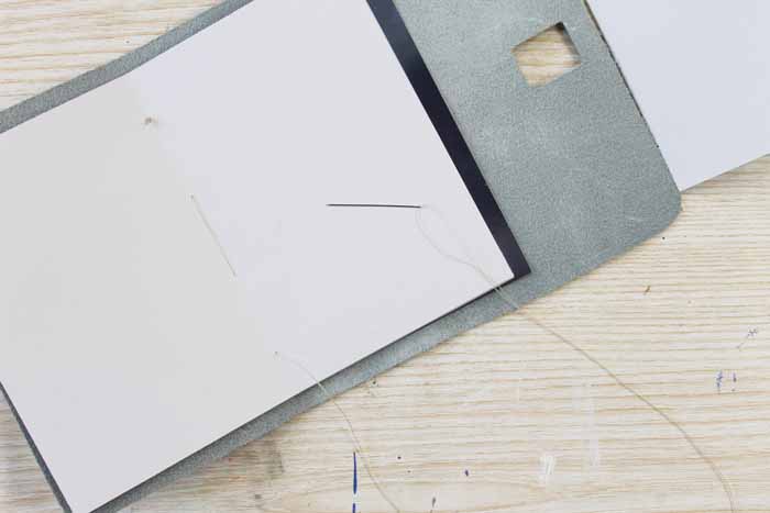 Use a needle and thread to attach the paper inserts along the binding of your leather journal