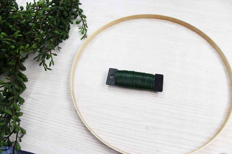 embroidery hoop on a table with floral wire