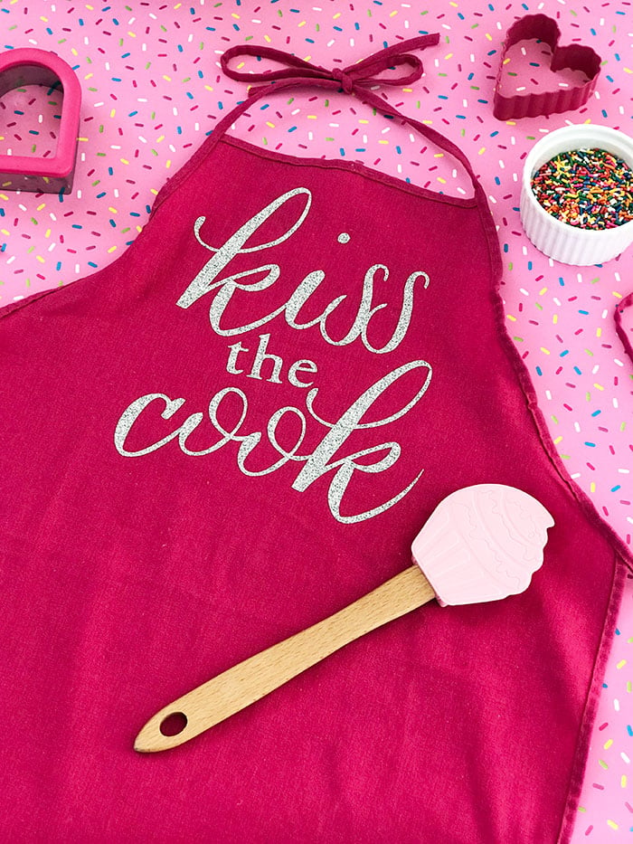 Make this DIY kiss the cook apron as a gift or for yourself!  It is super easy with a Cricut machine and iron-on vinyl!
