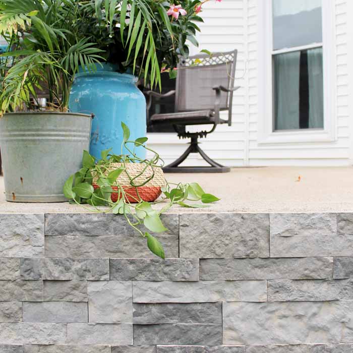 plants on a porch with stone veneer sides