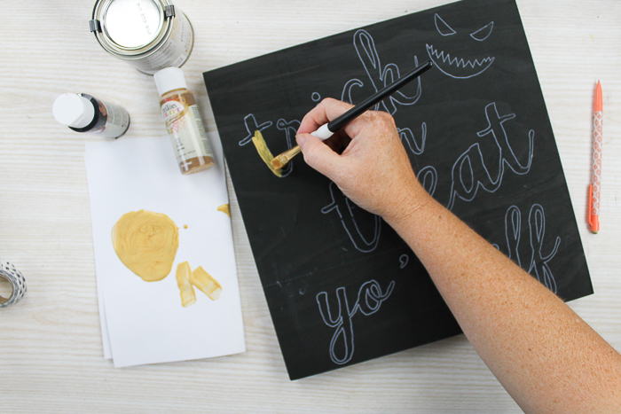 adding gold paint to a black sign