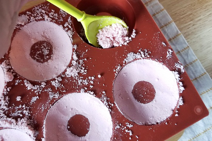 adding bath bomb mixture to donut mold