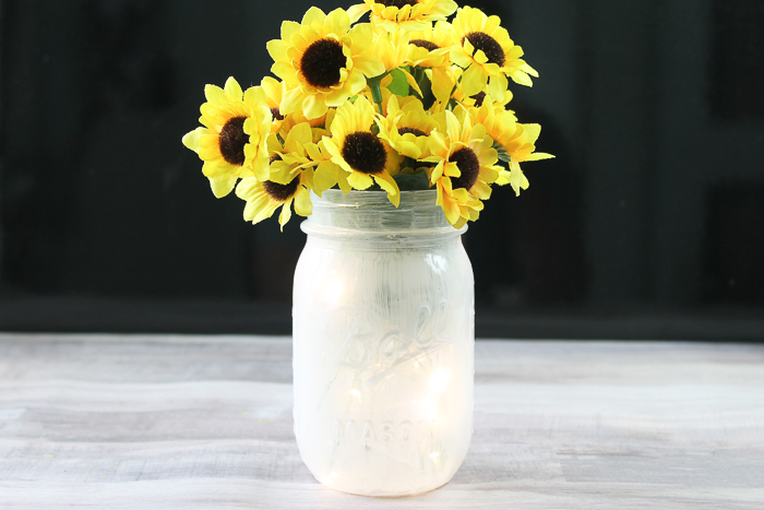 painted mason jar filled with fairy lights and topped with flowers