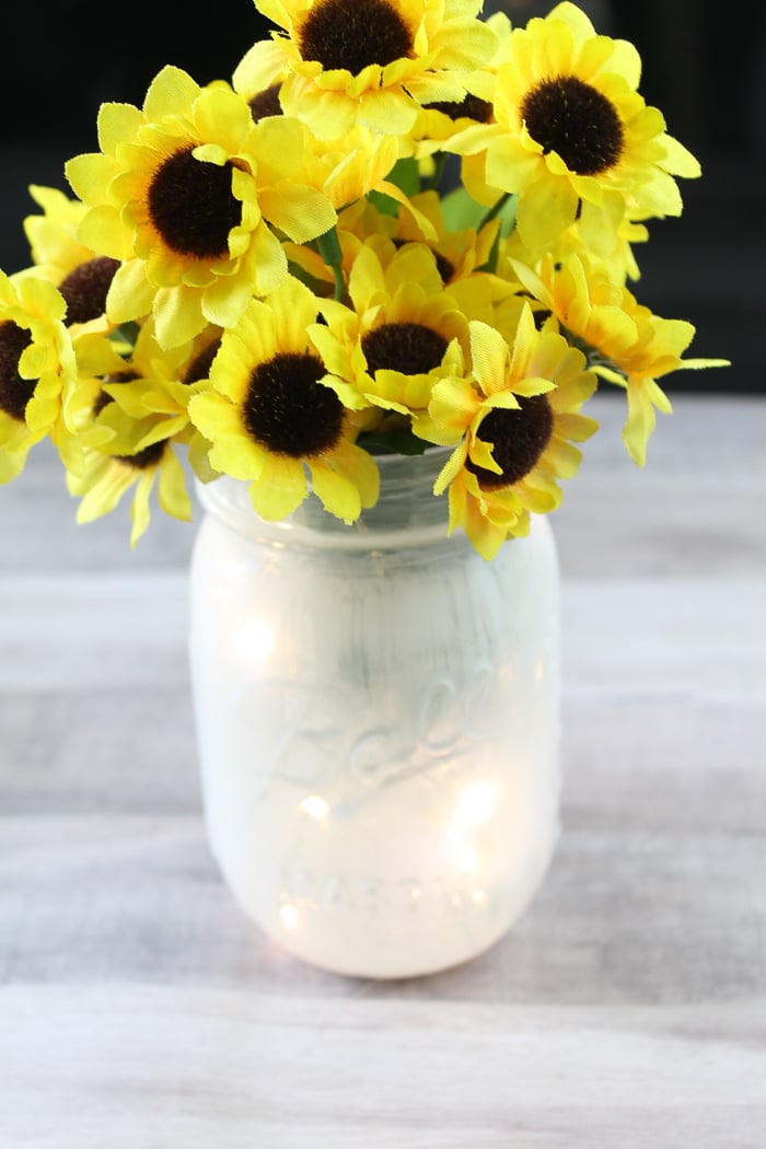 painted mason jar with sunflowers coming out of the top of the jar.