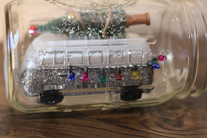 adding christmas ornaments inside of a mason jar