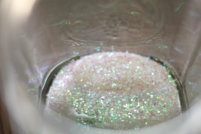 Easy Snow Globe in a Jar adding glitter to a mason jar