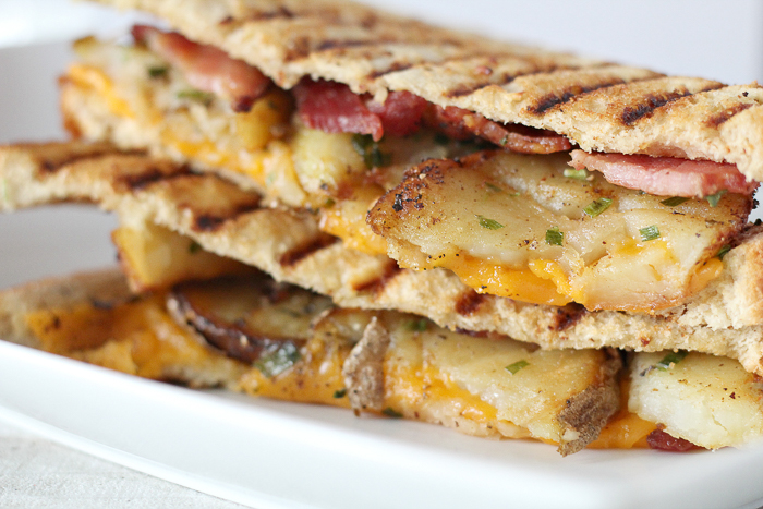 A close up of a sandwich on a plate, with Cheese and Bacon