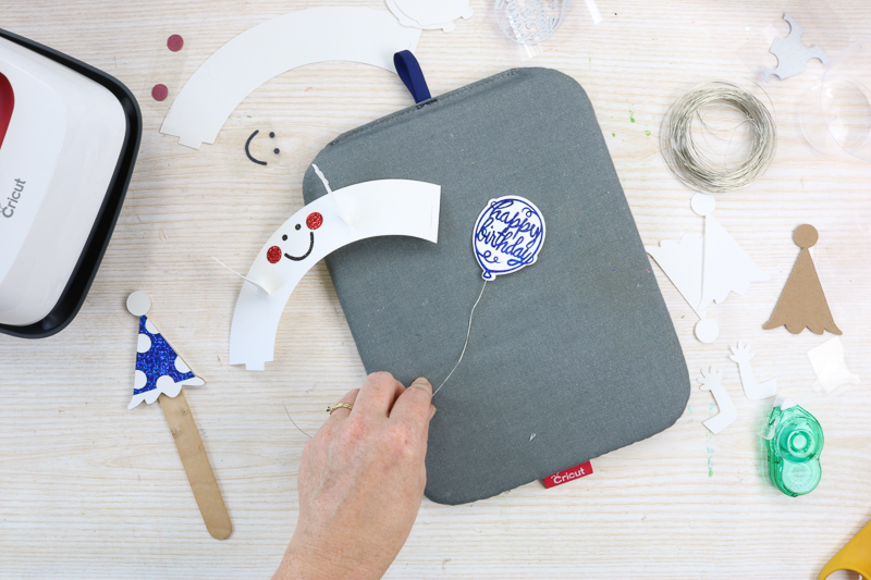 Adding a wire string to a balloon to add to a cupcake.