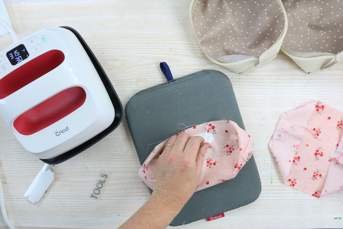 Adding iron on organization labels to fabric storage bins.