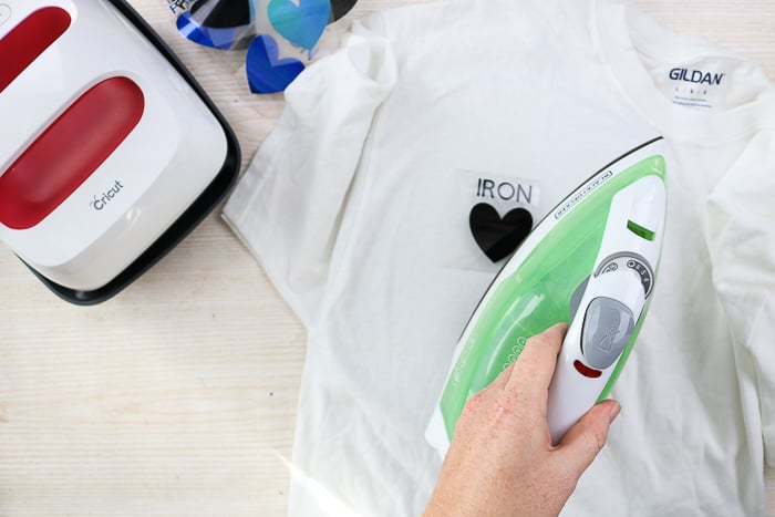 Using an iron to add heat transfer vinyl to a shirt.