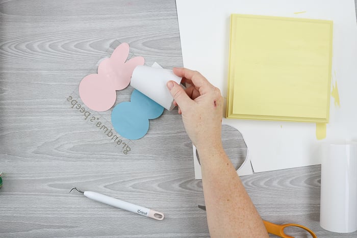 Peeling backing paper from vinyl to make grandma's peeps sign for Easter.