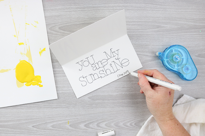 writing the child's name and date inside the card for Mom