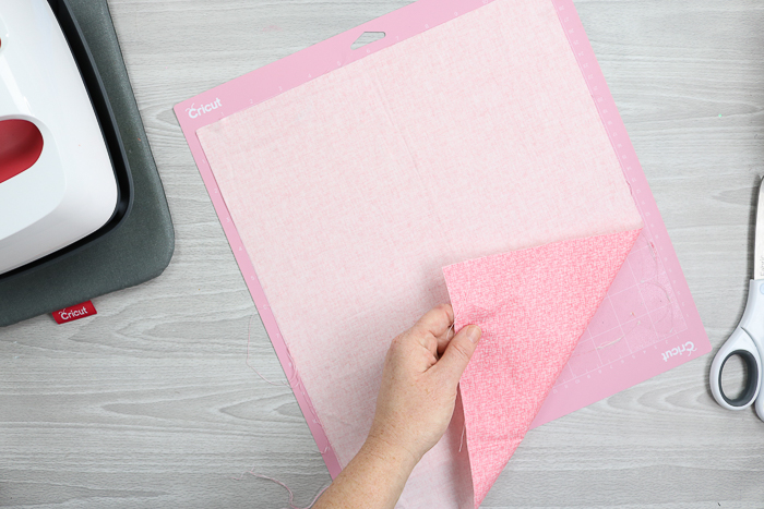 Adding fabric to the pink fabric mat for the Cricut Maker.