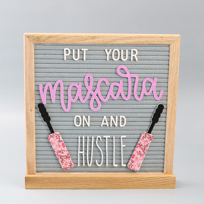 Grey letter board with quote and mascara wands