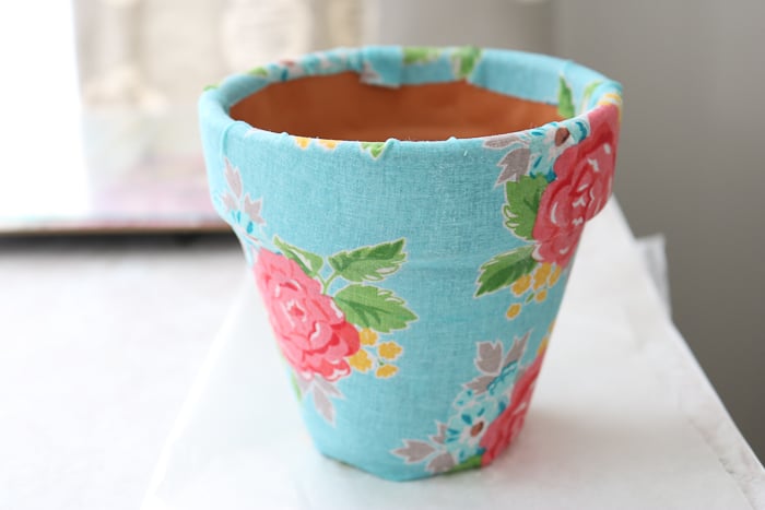 Coat the whole planter in Mod Podge, sealing the fabric to the terracotta planter